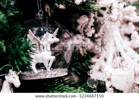 Glass toy with white unicorn inside on Christmas tree. Festive concept.