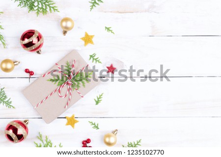 Christmas background concept. Top view of Christmas gift box with spruce branches, pine cones, red berries and bell on white wooden table background.