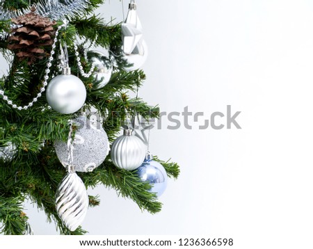 Silver Christmas decorations on a spruce branch on a white background