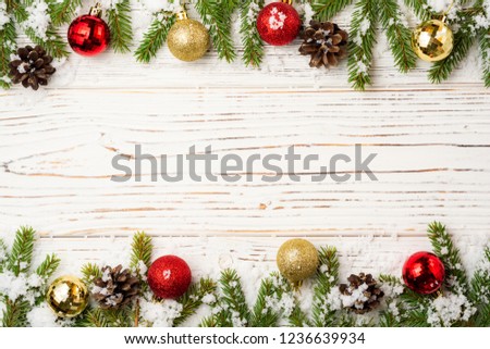 Christmas wooden background with fir branches, pine cones, snow and decorations. Top view with copy space.
