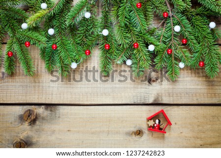 Wide Christmas border composed of fresh fir branches and ornaments in red and white on wood background.
