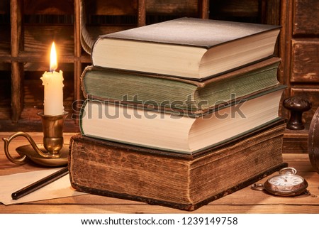 Old book on wooden table by candlelight