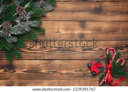 Christmas background with fir tree and gift box, pine cones on wooden table. New year decor top view with copy space for your design.