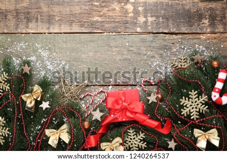 Christmas fir tree branches with decorations and gift box on grey wooden table