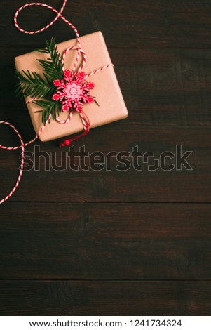 Christmas gift or present box wrapped in craft paper with decoration on rustic wooden background in festive arrangement, new year celebration concept, cozy atmosphere under the fir branches copy space