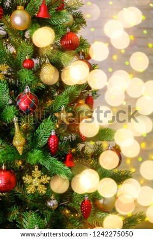 Decorated Christmas tree on soft yellow lights with bokeh effect background. Festive composition with fir and blurry sparkling backdrop, new year holiday decorations. Close up, copy space.