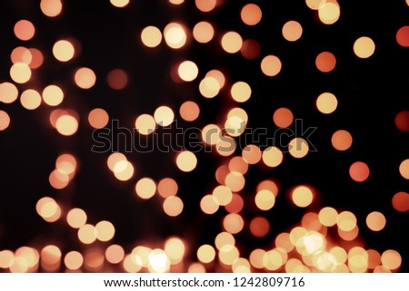 Yellow and orange Christmas tree bokeh on black background of defocused glittering lights, Christmas background pattern concept.
