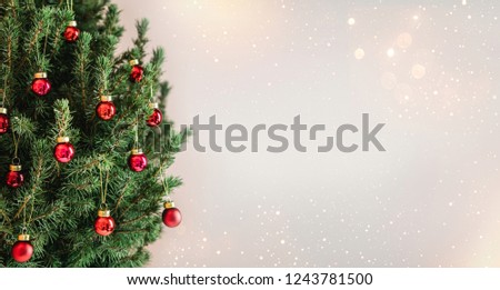 Christmas tree with red Christmas decorations on holiday background with snow, blurred, sparking, glowing. Happy New Year and Xmas theme