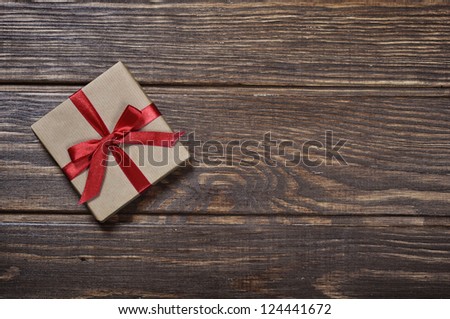 Gift box with red ribbon over wooden background