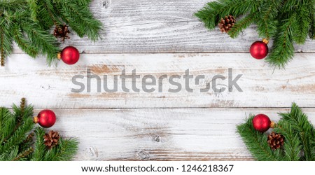 Christmas Evergreen branches and red ball decorations in all corners on white vintage wood