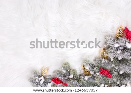 Border from red berries and branches fur tree on  white  fur  background. Decorative christmas composition. Selective focus. Place for text. View from above. Vertical image.
