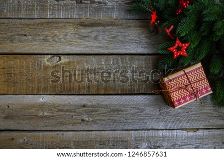 Christmas background with decorations and gift box on dark wooden board. Christmas gift, stars, fir branches. Toned image with copy space.