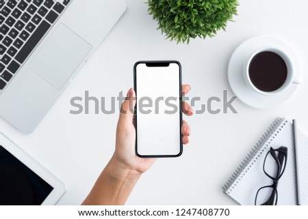 Hand holding new big smartphone with blank screen for mockup, top view, copy space