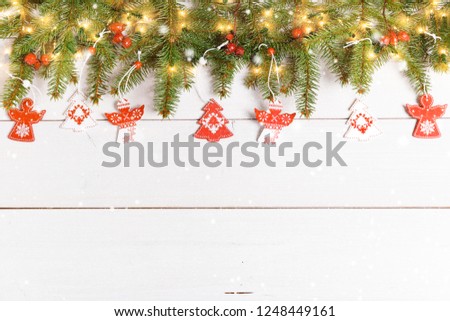 Christmas composition. Christmas tree decorated with white and red angels, red rosehip berries on a white wooden background. Christmas, new year, winter concept. Flat lay, top view, copy space