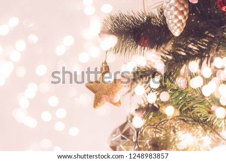 Close up of star hanging on Christmas tree with gold ,red, metal elegant element decoration home and holiday party with blurry light round bokeh background.