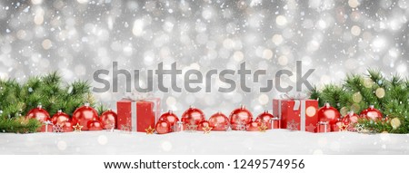 Red christmas baubles and gifts lined up on grey snowy background 3D rendering