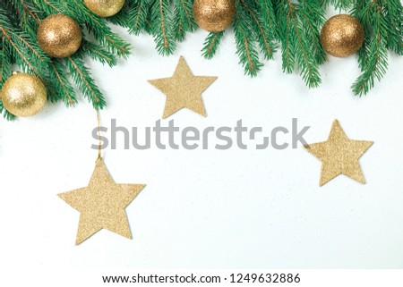 Christmas background for a congratulatory inscription. Green Branches if frame a white background. It is decorated by New Year's gold spheres and stars
