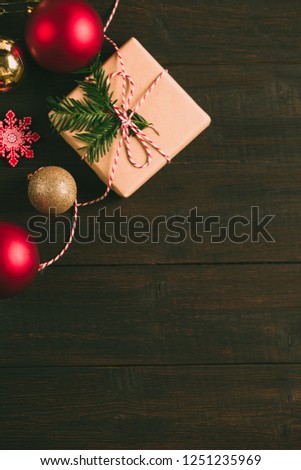 Christmas gift or present box wrapped in craft paper with decoration on rustic wooden background in festive arrangement, new year celebration concept, cozy atmosphere under the fir branches copy space
