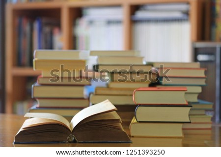 Close-up of old book opened on library table many books stacked as backgrounds selective focus and shallow depth of field
