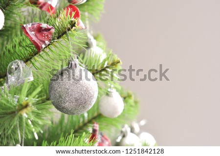 photo of decorated christmas tree. shiny balls, gray ornaments, bows on green branches. New year photo. Use for background, invitation, greeting card.