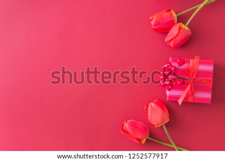 Valentines day composition with red tulips and gift box on a red background. Flat lay, top view