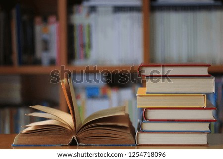 Close-up of old book opened on library table book stack with bookshelf as background selective focus and shallow depth of field