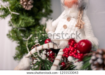 Little doll sitting on a holiday wreath