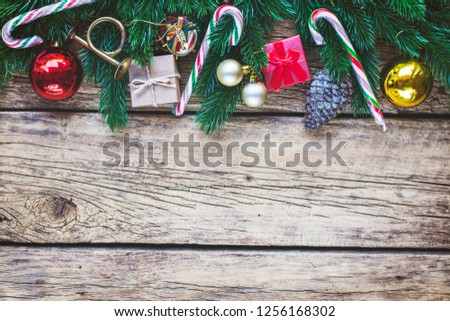 Vintage Christmas background with fir tree branches and traditional festive ornaments on a rustic wooden board