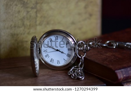 Pocket watch with Roman numbers on the table - isolated
