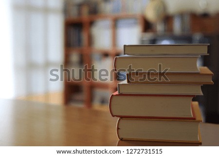 Close-up pictures of many books stacked on the table in the library Bookshelf in the background selective focus and shallow depth of field