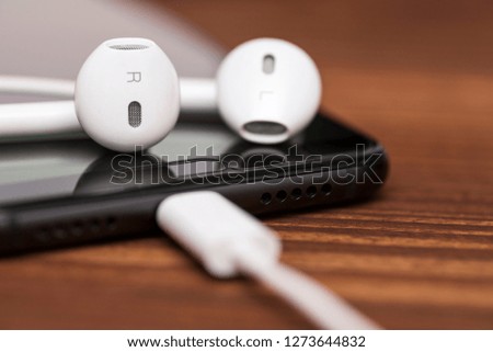 Smartphone with earphones on color background. Smartphone and earphone on wooden background. Close-up of smart phone with headphones on a wooden background