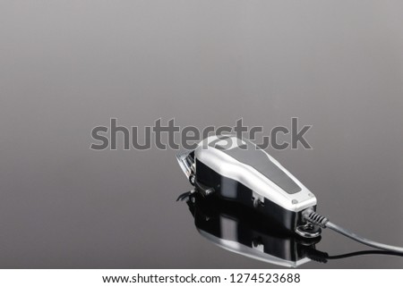 Electric hand-held hair clipper with accessory  for hair salon or barber shop on the grey mirror background with copy space