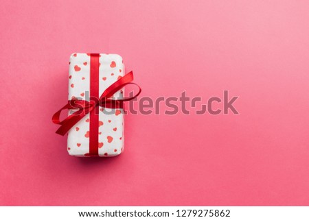 Gift box with red hearts on coral wooden background.