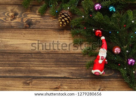 Fir tree branches with Christmas decoration and toy Santa Claus against old vintage style wooden planks. Christmas/New Year concept. Christmas card theme.