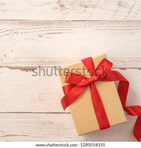 Kraft gift box with beautiful red ribbon bow, concept of giving present idea and Valentine's, anniversary, mother's day and birthday surprise, flat lay, topview, copyspace