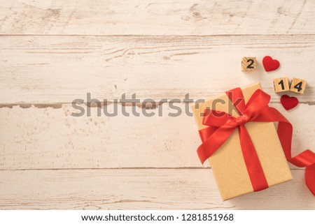 Kraft gift box with beautiful red ribbon bow, concept of giving present and Valentine's, anniversary, mother's day and birthday surprise, flat lay, topview, copyspace