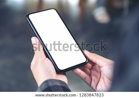Mockup image of hands holding black mobile phone with blank white screen 