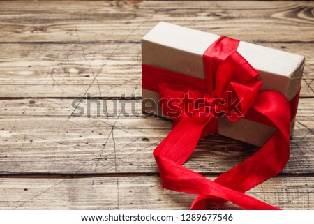 Concept Valentine's Day. Gift box with red bow on wooden table. copy space.