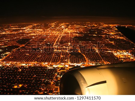 Flying over the night city by plane. The view from the window of a passenger plane during the flight, the wing of the turbine engine of the aircraft.