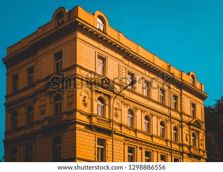 Facade of a historic town house with carved stone ornamentation and stylish arched windows in the warm glow of the setting sun