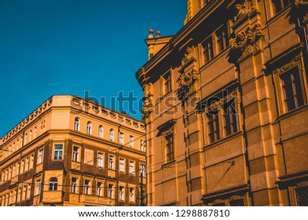 Historic architecture in Prague, Czech Republic looking up at the stone facades od multi-storey townhouses in evening light under a clear blue sky