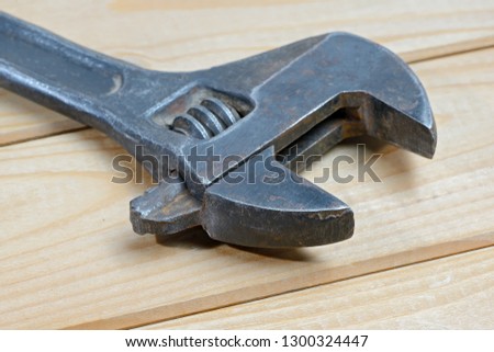 Dirty black adjustable wrench on a wooden background. Old spanner. Close up