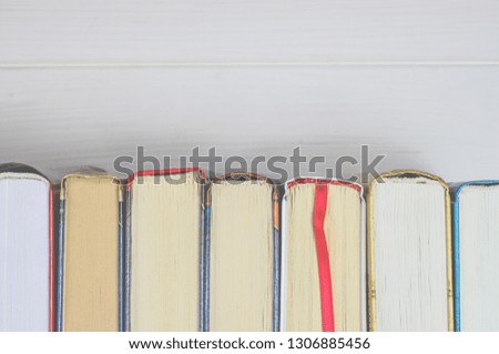 Lots of colourful thick open books stand on a white background