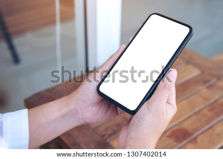 Mockup image of a hand holding black mobile phone with blank white desktop screen