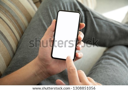 male hands holding phone with isolated screen on the sofa in the room