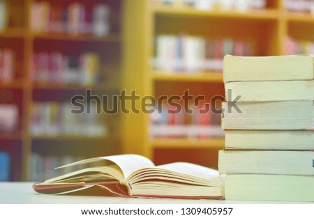 Stack of books in the library and blurred bookshelf in the library room, selective focus