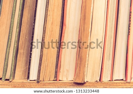 Stack of many old books on shelf in book store.