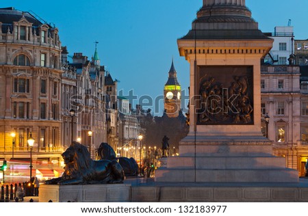 Sculpture lying lions at Nelson's Column pedestal in Trafalgar Square. Whitehall Street and Big Ben in the distance. Twilight