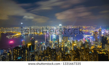 Aerial Skyline Cityscape and Light Trail from Ferry Boats Traffic of Victoria Bay with Countless Skyscrapers shot from Victoria Peak at Night Time in Never Sleep City Hong Kong.