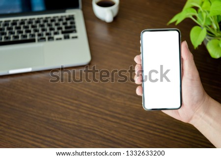 Mockup image man hand holding texting using black mobile,cell phone at desk with copy space,white blank screen for text.concept for contact business,people communication,technology electronic device